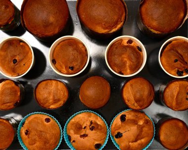 Fırında pişmiş Paskalya kekleri, çeşitli yuvarlak teneke kutular içinde, siyah bir fırın pişirme çarşafında..