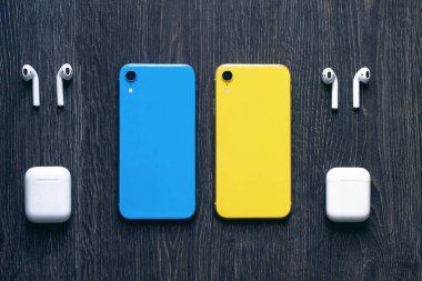 iki renkli telefonlar ve kablosuz bluetooth kulaklıklar. Mavi ve sarı telefon 