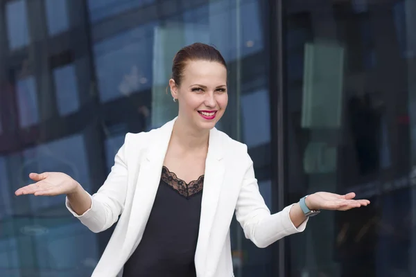 Glad to see you! Nice to meet you!  Beautiful happy young business woman in formal weather, suit making a scale with her arms, hands  wide open, look at camera smiling. Welcome sign, greeting gesture.