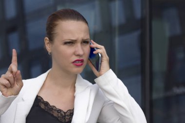 Kızgın hoşnutsuz genç iş kadını cep telefonuyla konuşarak, müşteri desteğini arayarak. Tatsız konuşma, kötü hizmetten şikayet etme, tartışma, konuşma sırasında kızgınlık, çatışma.