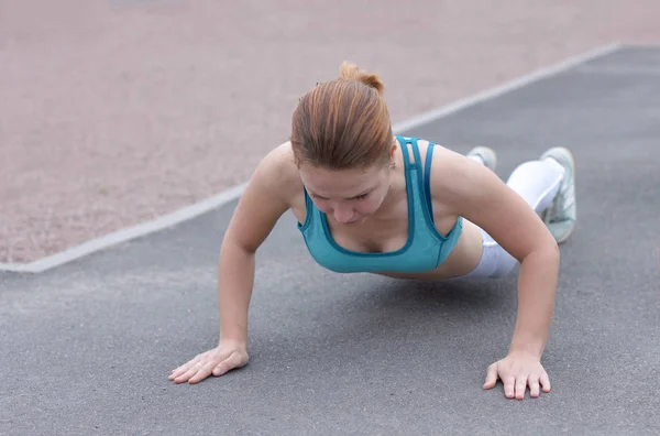 運動をする強い運動の女の子 屋外のスポーツグラウンドでのトレーニング プッシュアップをしている女性 健康的なアクティブなスポーツフィットネスライフの概念 ワークアウト ジム外 — ストック写真