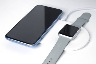 Cep telefonu, akıllı telefon ve kablosuz şarjla şarj oluyor. Yeni cihazlar, ekipmanlar. Modern teknoloji konsepti. Hayat, cihazların bileşimi telefon, saat, şarj aleti. Saldırmak için kolay yol.