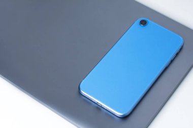 Yeni modern cihazların, cihazların, mavi cep telefonu akıllı telefonun ve gri alüminyum dizüstü bilgisayarın yaşam bileşimi. Teknoloji konsepti. Beyaz arka planda düz yatıyordu. Defter ve telefon. Model.