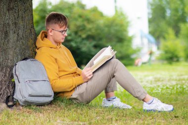 Yakışıklı bir adam, genç bir adam ya da öğrenci. Bir yaz parkında kitap okuyor. Ağaçlara yaslanmış, yerde oturuyor. Sırt çantası ve ders kitabı olan gözlüklü çocuk sınava hazırlanıyor. Ders.
