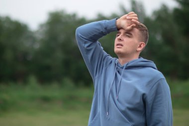 Hasta hasta adam, sıcaktan muzdarip genç adam, yüksek ateş, dışarıda baş ağrısı, elini kafasında ve alnında tutuyor. Kötü, sağlıksız, sağlıksız hissediyorum. Coronavirus covid-19 belirtileri.