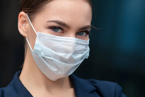 Portrait of beautiful serious business woman, young gorgeous pretty European girl in medical sterile protective mask against coronavirus, epidemic covid-19. Healthcare at job