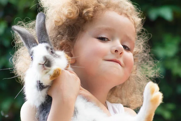 Niña feliz, jovencita sosteniendo un conejo o conejo en su mano, sonriendo. Feliz Pascua. — Foto de Stock