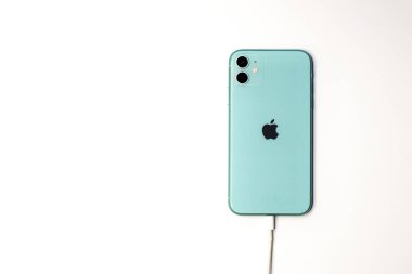 Saint-Petersburg, Rusya - 09.09.20: Apple yeni akıllı telefon yeşil iPhone 11 beyaz arka planda yıldırım kablosuyla şarj ediliyor. 