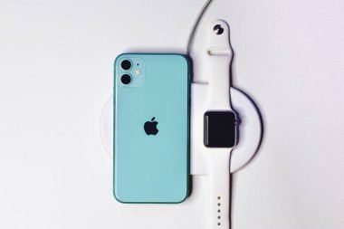 Saint-Petersburg, Rusya - 09.09.20: Apple 'ın yeni akıllı telefonu yeşil iPhone 11, akıllı Apple Watch ile birlikte kablosuz şarjla şarj ediliyor