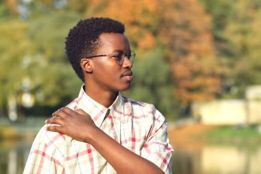 Altın sonbahar parkında gözlüklü Afrikalı Afro Amerikalı yakışıklı bir adamın profil portresi.