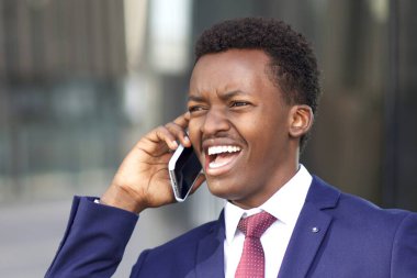 Komik siyah Afrikalı Afro-Amerikalı rahatsız iş adamı arıyor, cep telefonuyla konuşuyor, tartışıyor, tatsız olumsuz konuşmalar yapıyor. İş adamı bağırıyor, bağırıyor..