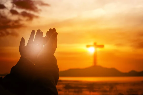 Christian woman praying worship at sunset. Hands folded in praye