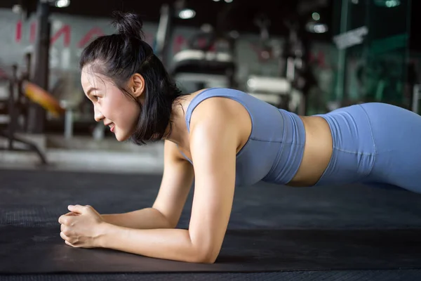 woman doing plank exercise on mat in gym. woman exercise trainer