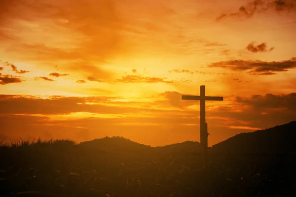 Cruz de madeira conceitual ou símbolo de religião sobre um céu pôr do sol com — Fotografia de Stock