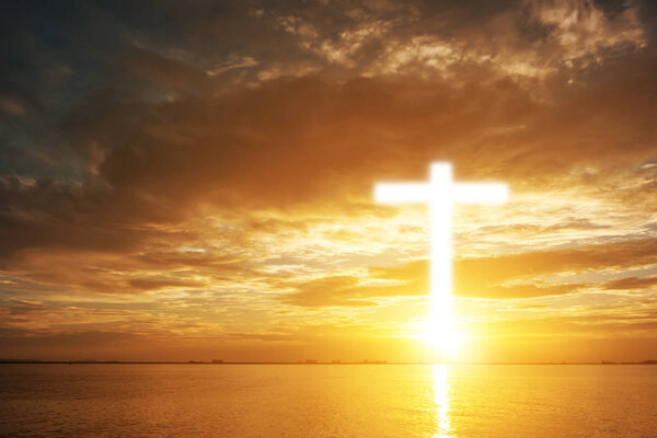 Conceptual wood cross or religion symbol shape over a sunset sky