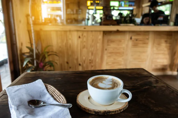 The ceramic cup of hot cappuccino coffee on the wooden table in — Stock Photo, Image