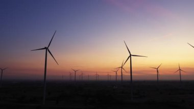 Enerjiyi Kurtarma Enerjisi 'nin hava görüntüsü 4k video formatında. Gün batımında hava görüntüsü. İHA, güneş doğarken rüzgar türbinlerini güzel bulutlarla görüntüler. Küresel ısınma kavramı ve yeşil enerji.