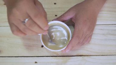 Top view of Person hand steering coffee in a cup with spoon. Breakfast morning of a cup hot black coffee on wooden background. footage b-roll scene 4k. home made coffee. 