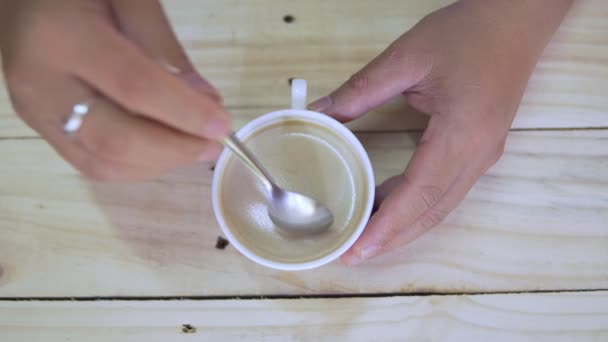 スプーンでカップに人の手ステアリングコーヒーのトップビュー 木製の背景にカップホットブラックコーヒーの朝食 映像B Rollシーン4K 自家製コーヒー — ストック動画
