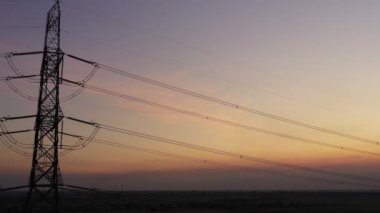 Aerial view drone shot. High voltage metal post. High-voltage towers in the forest with moving at sunset with twilight sky and clouds background. footage video b roll 4k.