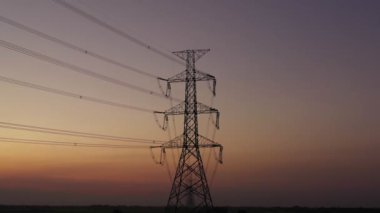 Aerial view drone shot. High voltage metal post. High-voltage towers in the forest with moving at sunset with twilight sky and clouds background. footage video b roll 4k.