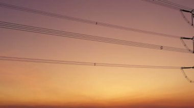 Aerial view drone shot. High voltage metal post. High-voltage towers in the forest with moving at sunset with twilight sky and clouds background. footage video b roll 4k.