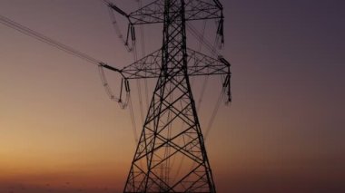 Aerial view drone shot. High voltage metal post. High-voltage towers in the forest with moving at sunset with twilight sky and clouds background. footage video b roll 4k.