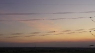 Aerial view drone shot. High voltage metal post. High-voltage towers in the forest with moving at sunset with twilight sky and clouds background. footage video b roll 4k.