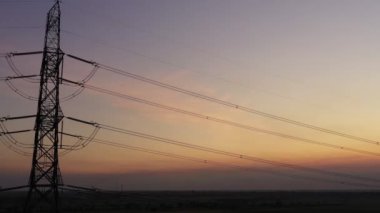 Aerial view drone shot. High voltage metal post. High-voltage towers in the forest with moving at sunset with twilight sky and clouds background. footage video b roll 4k.