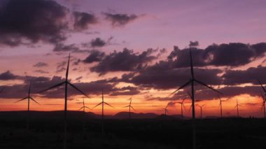 Enerjiyi Kurtarma Enerjisi 'nin hava görüntüsü 4k video formatında. Gün batımında hava görüntüsü. İHA, güneş doğarken rüzgar türbinlerini güzel bulutlarla görüntüler. Küresel ısınma kavramı ve yeşil enerji.