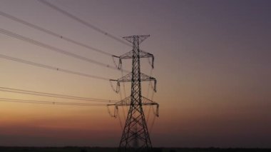Aerial view drone shot. High voltage metal post. High-voltage towers in the forest with moving at sunset with twilight sky and clouds background. footage video b roll 4k.