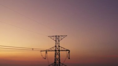 Aerial view drone shot. High voltage metal post. High-voltage towers in the forest with moving at sunset with twilight sky and clouds background. footage video b roll 4k.