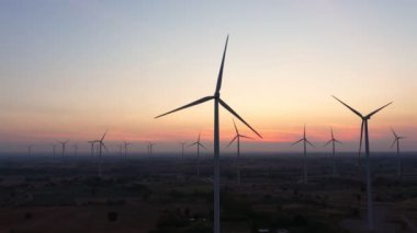 Enerjiyi Kurtarma Enerjisi 'nin hava görüntüsü 4k video formatında. Gün batımında hava görüntüsü. İHA, güneş doğarken rüzgar türbinlerini güzel bulutlarla görüntüler. Küresel ısınma kavramı ve yeşil enerji.