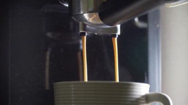 Kahve makinesinin fincanından dökülen kahvenin görüntüsü. Ev yapımı sıcak Espresso. Filtre tutacağı kullanılıyor. Taze kahve akıyor. Sabahları kavrulmuş sade kahve içmek.. 