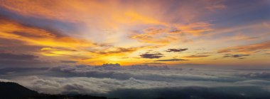 Gün batımı ve bulutlu güzel gökyüzü. Fantastik sisli manzaranın panoraması sabah güneş doğarken parlıyordu. Yüksek dağların sisli örtüsüyle güzel bir manzara. Güzel bir ışıkla yoğun sis.