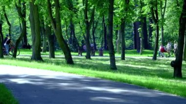 Motosikletli bir kız yaz parkında bir ara sokakta geziyor.