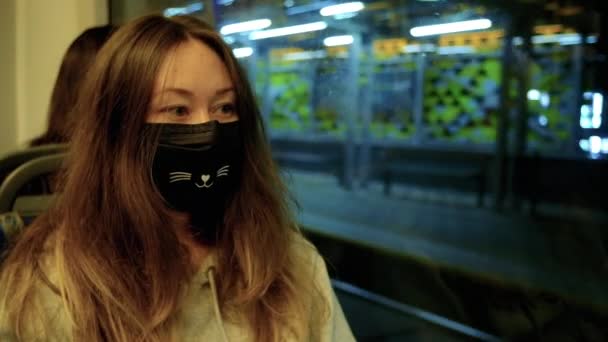 Čínská dívka v lékařské masce jezdí ve večerní městské dopravě — Stock video