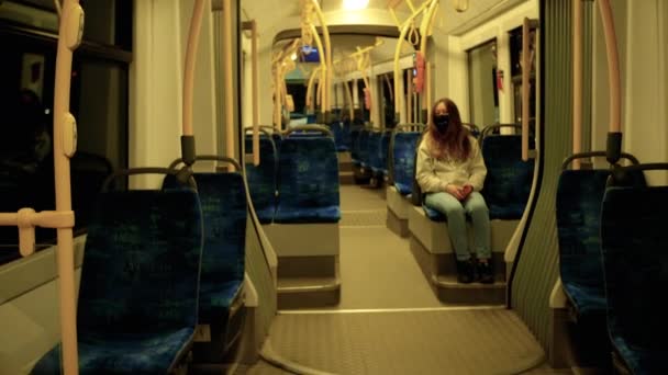 Китайська дівчина в медичній масці їде у вечірній міський транспорт. — стокове відео