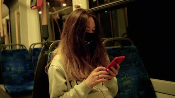 Menina chinesa em uma máscara médica passeios no transporte da cidade à noite — Vídeo de Stock
