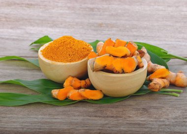 Zerdeçal tozu ve ahşap zemin üzerine taze zerdeçal.