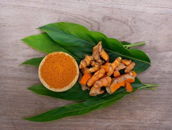 Zerdeçal tozu ve ahşap zemin üzerine taze zerdeçal.