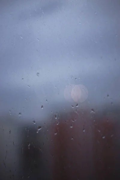 Primer plano de las gotas de lluvia en la ventana sobre un fondo borroso de t — Foto de Stock