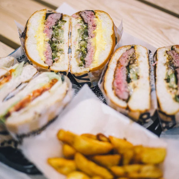 Hamburguesas de carne cortadas de cerca y papas fritas en una bandeja en un café — Foto de Stock