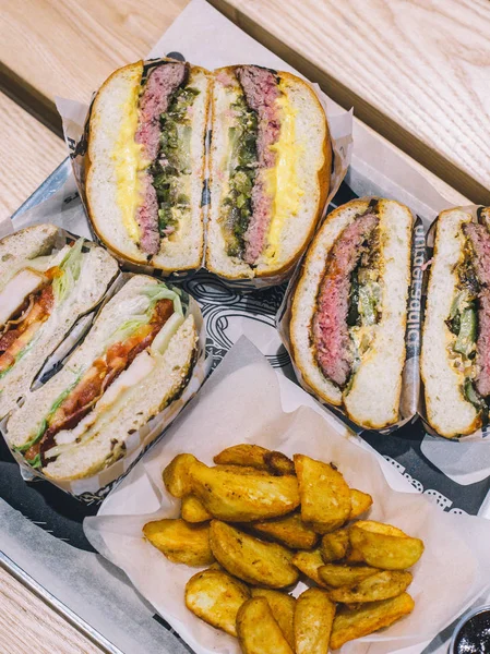 Hamburguesas de carne cortadas de cerca y papas fritas en una bandeja en un café — Foto de Stock