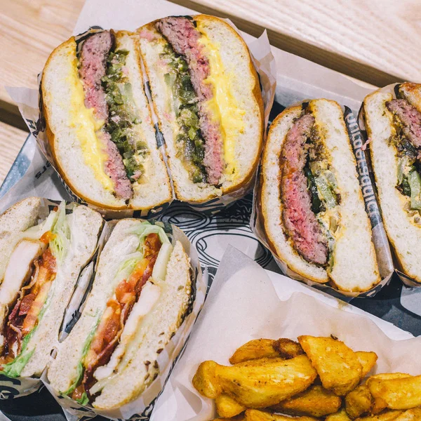 Hamburguesas de carne cortadas de cerca y papas fritas en una bandeja en un café — Foto de Stock