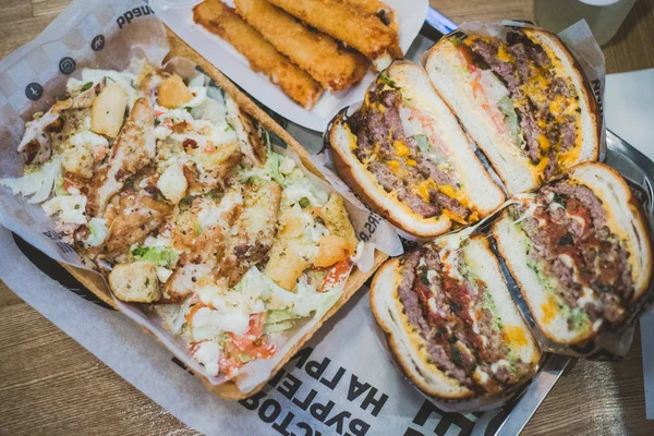 Hamburguesas de carne en rodajas de cerca, ensalada César y palitos de queso mienten — Foto de Stock