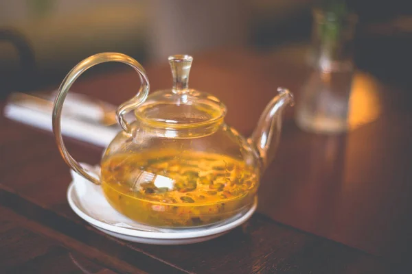 Close-up transparent glass teapot with sea buckthorn tea on the — Stock Photo, Image