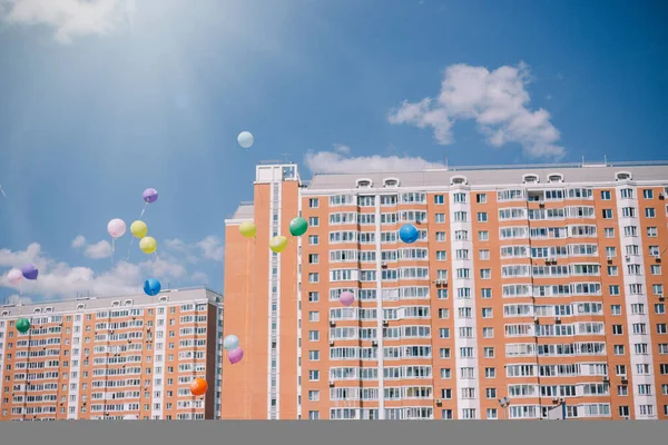 Balloons against the blue sky, clouds and residential buildings.
