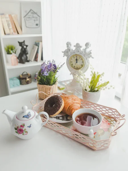 Una bandeja con una tetera, una taza de té, un platillo, croissant y un do — Foto de Stock