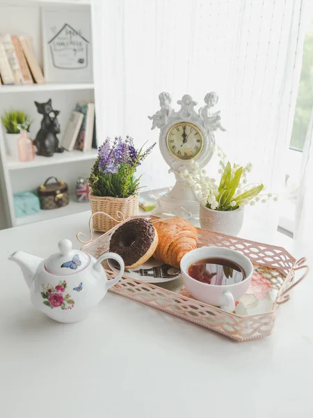 Una bandeja con una tetera, una taza de té, un platillo, croissant y un do — Foto de Stock